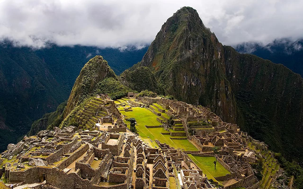 The Machu Picchu citadel and its terraces below Huayna Picchu, under breaking storm cloud