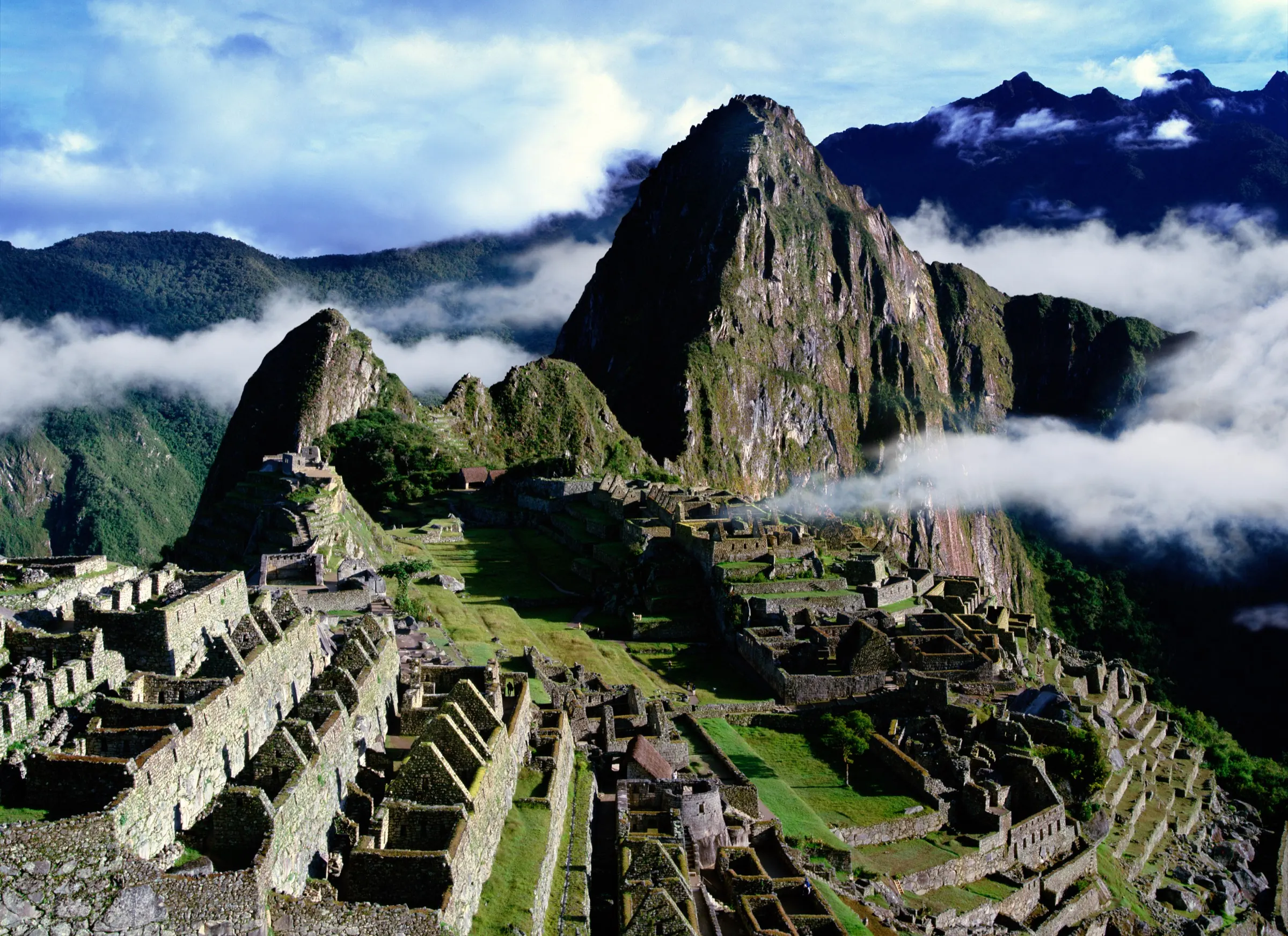 Machu Picchu citadel with Huayna Picchu rising behind it and clouds below in the valley