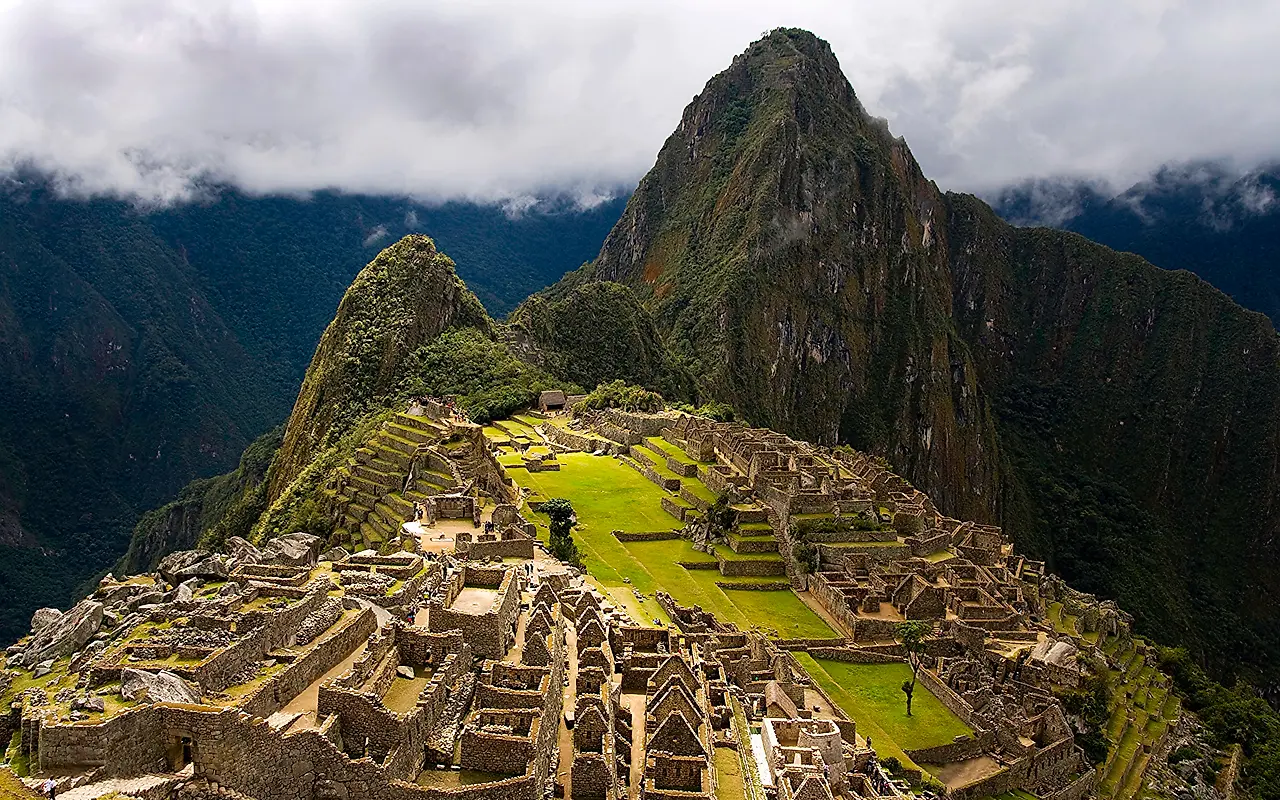 The Machu Picchu citadel and its terraces below Huayna Picchu, under breaking storm cloud
